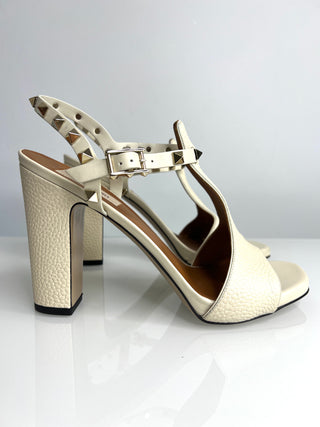 Beige high-heeled shoe with a strap on a white background