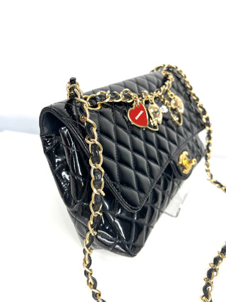 Black quilted handbag with gold chain and heart-shaped charm on a white background