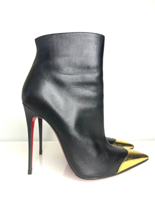 Christian Louboutin Calamijane Booty black leather ankle boot with a pointed toe featuring a metallic gold cap and iconic red sole.