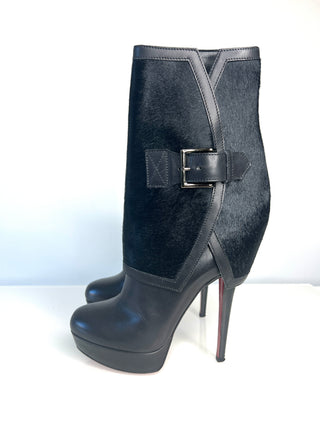 A pair of Christian Louboutin Armony black high-heeled ankle boots with a textured upper, a side buckle strap, and red sole.
