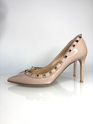 Beige high-heeled shoes with studded design on a white background