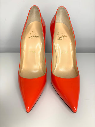 Pair of red high-heeled shoes with gold soles on a white background