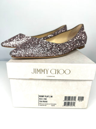 Silver glittery flats on a Jimmy Choo box with a white background