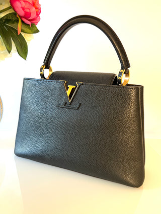 Louis Vuitton Capucines  black pebbled leather handbag with a top handle, gold-tone hardware, and a prominent V logo on the front