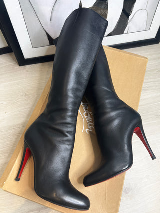 A pair of Christian Louboutin black leather knee-high stiletto boots with red soles.