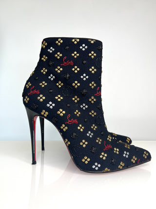 Black high-heeled boot with gold and red patterns on a white background
