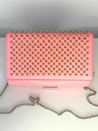 Pink studded handbag with a chain strap on a white background