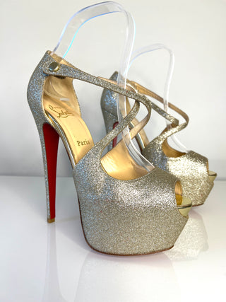 Gold glitter high heels with a red sole on a white background