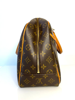 Brown leather handbag with gold monogram pattern on a white background