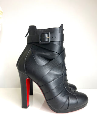 Black high-heeled boots with a strap and buckle on a white background