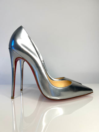 Silver high-heeled shoe on a reflective surface with a gradient background