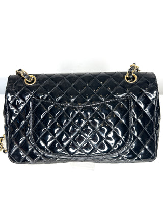 Black quilted handbag with gold hardware on a white background