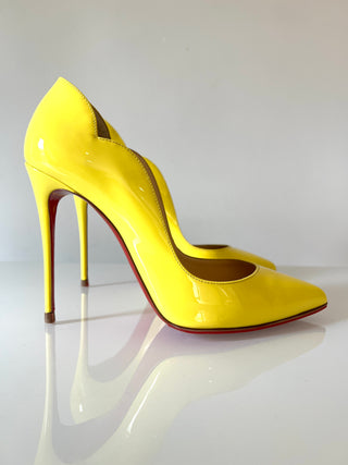 Yellow high-heeled shoes on a reflective surface with a white background