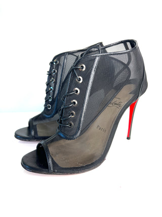 A pair of Christian Louboutin black mesh lace-up ankle boots with peep toes and signature red soles.