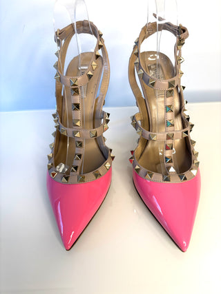 Pink high-heeled shoes with gold studded details on a white background