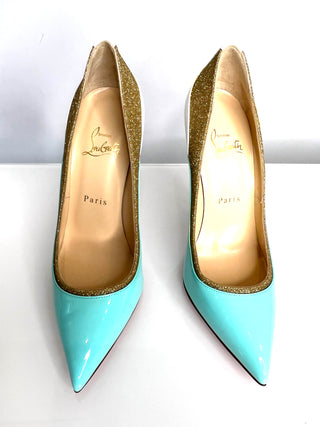 Pair of light blue high-heeled shoes with gold soles on a white background