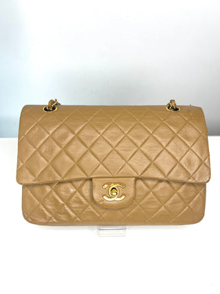 A vintage Chanel quilted flap shoulder bag in tan leather with gold-tone hardware and the iconic interlocking CC logo on the front.