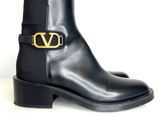 Black ankle boot with gold buckle on a white background