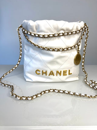 A white Chanel 22 quilted fabric bag with gold-tone chain strap and gold CHANEL lettering on the front