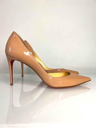 Pair of beige high-heeled shoes on a reflective surface with a white background