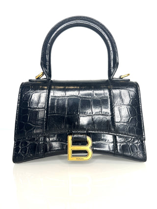Black crocodile-patterned handbag with gold 'B' logo on a white background