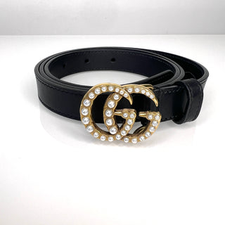 Black belt with a gold and pearl embellished buckle on a white background
