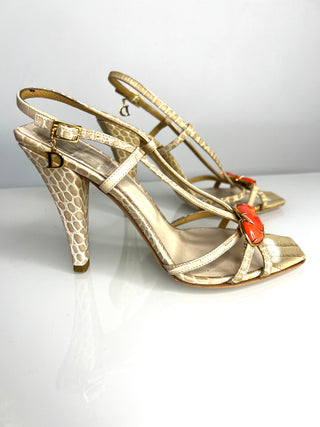 A pair of Christian Dior slingback high heels with a textured snakeskin pattern, featuring orange-red coral accent on the toe strap and a gold 'D' logo on the buckle.