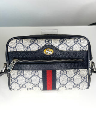 A Gucci crossbody bag in GG Supreme canvas with navy leather trim, featuring the signature red and green web stripe on the front pocket.