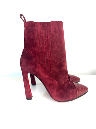 Christian Louboutin Me In The 90s burgundy red suede ankle boots with a high stiletto heel, a textured toe cap, and a signature red sole.