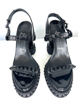 Black high-heeled sandals with detailed sole design on a white background