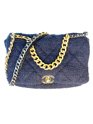 A large Chanel 19  quilted tweed shoulder bag in navy blue, featuring a gold-tone chain strap and a gold interlocking CC logo on the front flap,