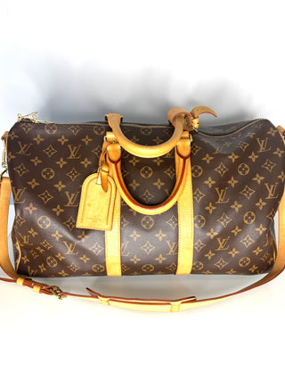 Designer handbag with monogram pattern and gold accents on a white background