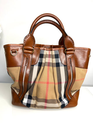 Designer handbag with checkered pattern and brown leather accents on a white background