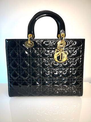 Christian Dior black patent leather Lady Dior handbag with quilted diamond pattern, gold-tone hardware, and a prominent interlocking D logo charm.