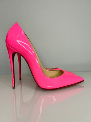 Shiny pink high-heeled shoe on a reflective surface with a neutral background