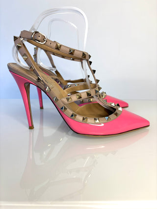 Pink high-heeled shoes with gold studded details on a white background